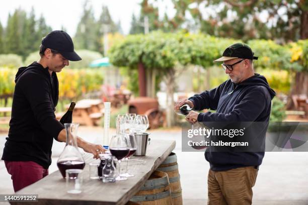 winemakers decanting wine from bottles with vineyard in background - california vineyard stock pictures, royalty-free photos & images