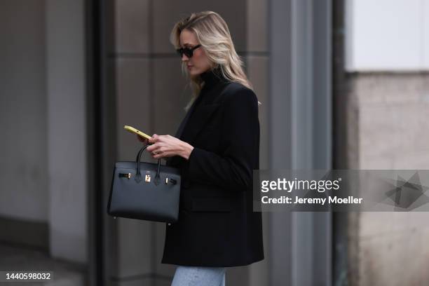 Mandy Bork wearing Saint Laurent black blazer, Hermes black leather Birkin bag, Celine black and gold logo belt, Agolde blue jeans, Liu Jo black...