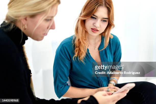 women who use smartphones in the waiting room - odontología cosmética fotografías e imágenes de stock
