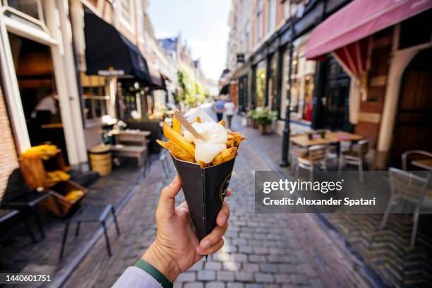 man eating french fries on the street, personal perspective - street food fotografías e imágenes de stock