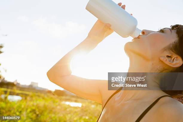 athletic woman drinking from water bottle - west asia stock-fotos und bilder