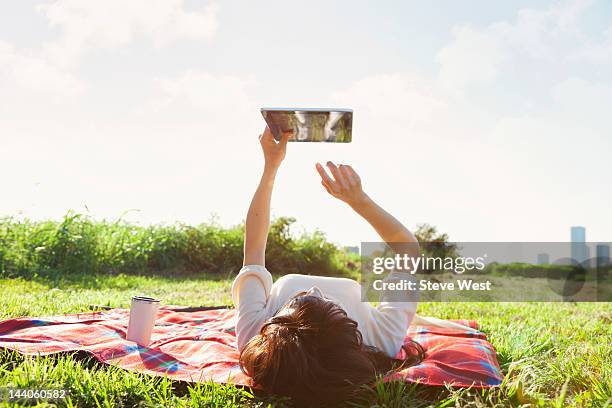 woman lying down using digital tablet - west asian ethnicity stockfoto's en -beelden