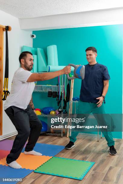 hombre haciendo ejercicios de fisioterapia en una clinica de rehabilitacion, con el quiropractico dandole indicaciones - fisioterapia 個照片及圖片檔