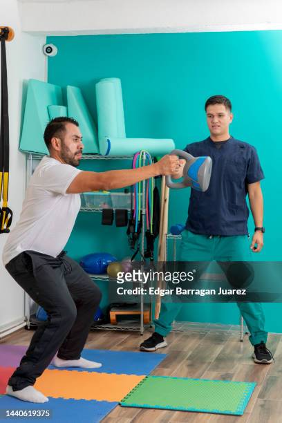 hombre haciendo ejercicios de fisioterapia en una clinica de rehabilitacion, con el quiropractico dandole indicaciones - hombre latino stock-fotos und bilder