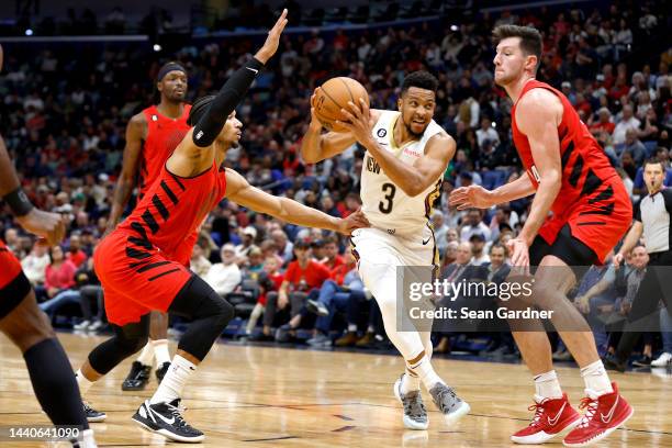 McCollum of the New Orleans Pelicans drives the lane as he is defneded by Josh Hart of the Portland Trail Blazers and Drew Eubanks of the Portland...