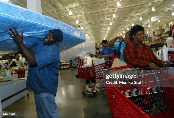 Carl Daniels of Brooklyn hoists a matress onto his shoulder as he waits in line at BJ's Warehouse October 1, 2002 at the Gateway Center in Brooklyn,...