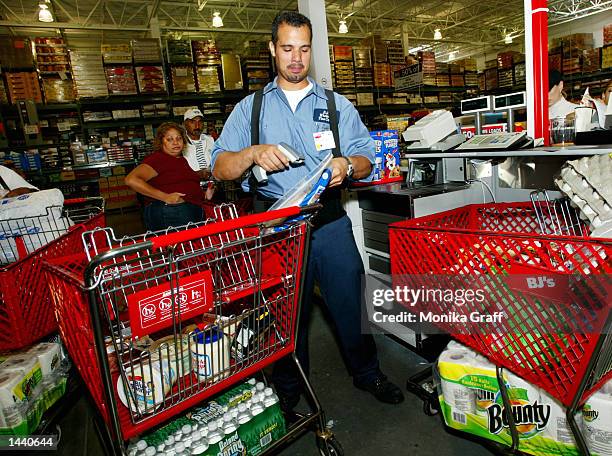 Manny Cruz scans items in the check-out line at BJ's Warehouse, where he works, October 1, 2002 at the Gateway Center in Brooklyn, New York during...