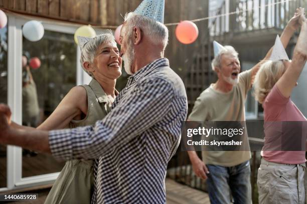 happy senior couples dancing during a birthday party on a terrace. - elderly birthday party stock pictures, royalty-free photos & images