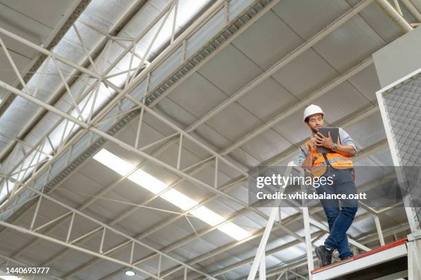 overseer wearing hard hat with tablet counts merchandise in warehouse. - storage solutions stock pictures, royalty-free photos & images