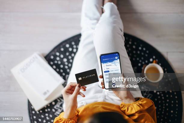 overhead view of young asian woman booking flight tickets on airline website online with smartphone and making payment with credit card at home. travel planning. booking a holiday online. travel and vacation concept. business person planning business trip - booking hotel foto e immagini stock