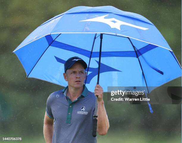 Luke Donald of England takes shelter under an umbrella on the second hole during Day Two of the Nedbank Golf Challenge at Gary Player CC on November...