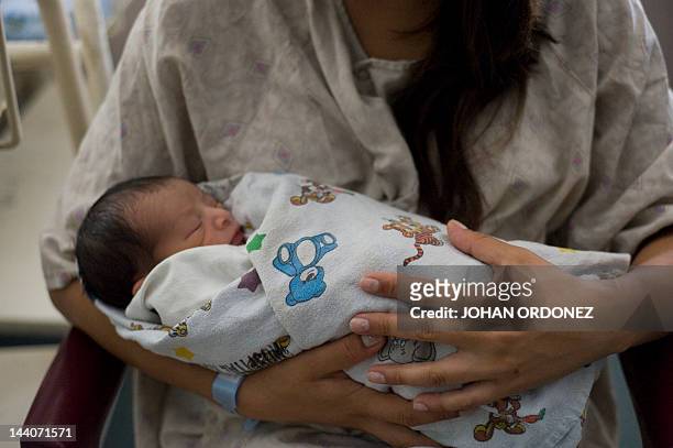 Woman holds her son a few hours after giving him birth at the Roosevelt Hospital in Guatemala City on May 09,2012. Guatemala on May 10 will celebrate...