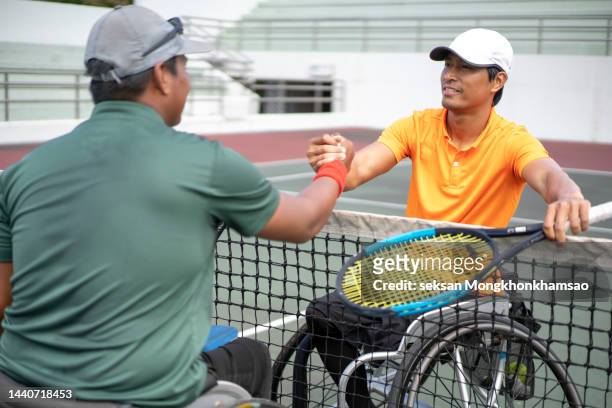 adaptive athletes shaking hands at net after wheelchair tennis match - wheelchair tennis stock pictures, royalty-free photos & images