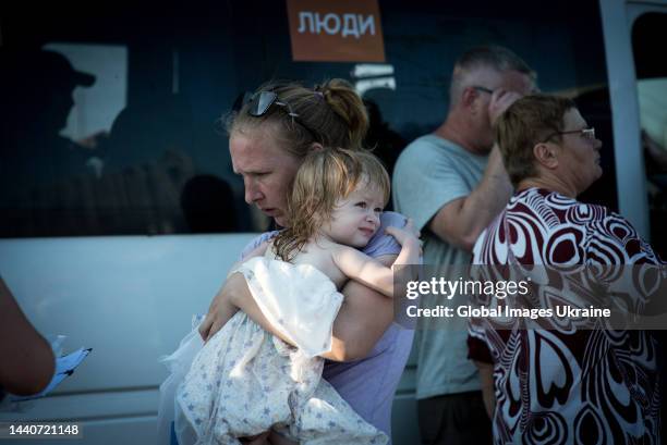 Mother holds a crying child in her arms near a bus with sign “people” that came from temporary occupied Kherson at the refugee hub on June 29, 2022...