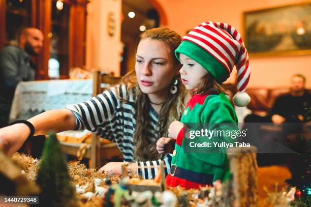 toddler enjoying christmas time with mother at christmas dinner. - christmas elf stock pictures, royalty-free photos & images