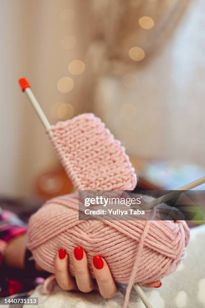gros plan d’une femme tenant une main boule de fil pastel rose et d’aiguilles à tricoter - travaux daiguilles photos et images de collection