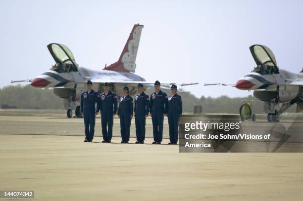 Six US Air Force male and female pilots standing at attention in front of their F-16C Fighting Falcons, known as the Thunderbirds before flying at...