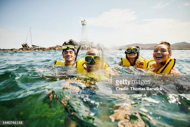 medium shot of smiling family on snorkeling tour in tropical ocean - travel stock-fotos und bilder