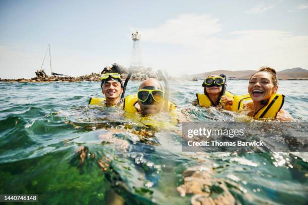 medium shot of smiling family on snorkeling tour in tropical ocean - family travel stockfoto's en -beelden