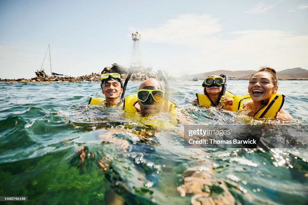 Medium shot of smiling family on snorkeling tour in tropical ocean