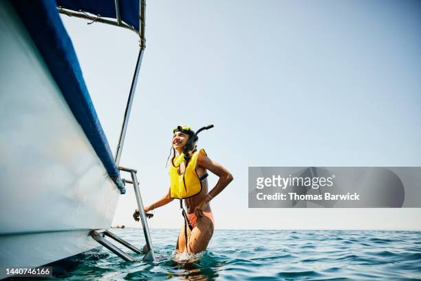 wide shot of girl climbing into boat after snorkeling tour in ocean - mexico black and white stock-fotos und bilder