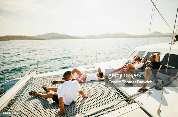 wide shot of families relaxing on deck of sailboat while on vacation - catamaran stockfoto's en -beelden