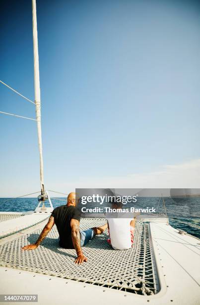 wide shot of father and son relaxing on sailboat during vacation - father son sailing stock pictures, royalty-free photos & images