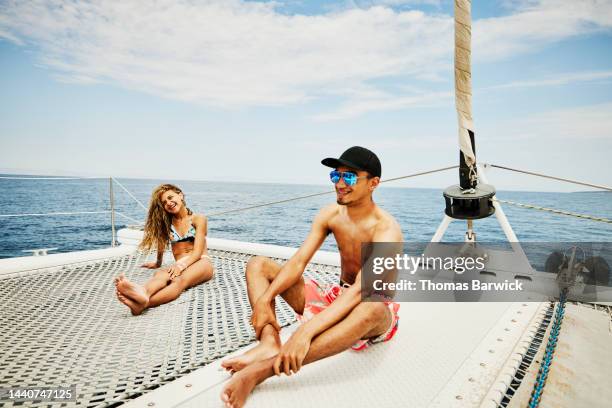 wide shot of laughing brother and sister relaxing on bow of sailboat - preteen girl no shirt stock pictures, royalty-free photos & images