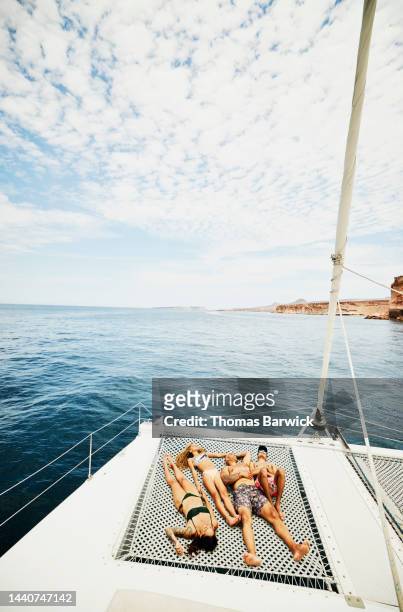 Wide shot of family sunbathing on deck of sailboat while on cruise