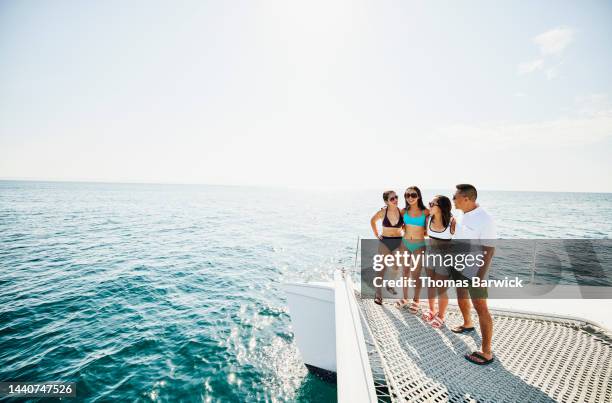 wide shot of smiling embracing family standing at bow of catamaran - baja california sur stock pictures, royalty-free photos & images