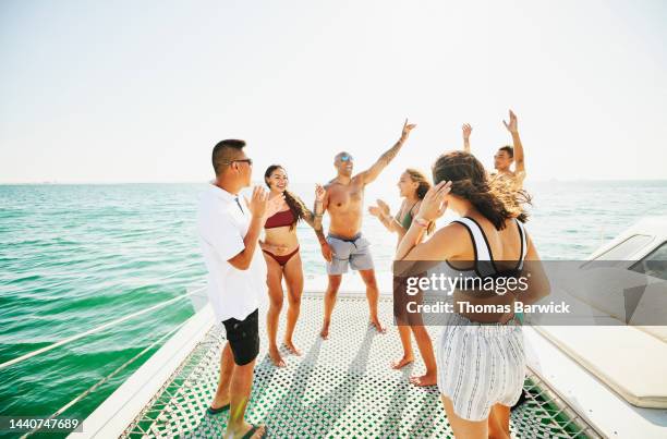 wide shot of smiling families dancing and singing on bow of sailboat - baja california sur stock-fotos und bilder