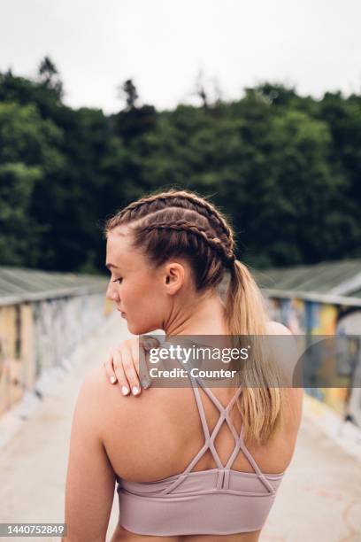 female athlete with braided hair looking down - sportbeha stockfoto's en -beelden