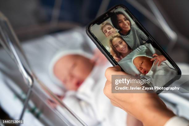 mother showing her newborn baby by videoconference to her family - coronavirus photos 個照片及圖片檔