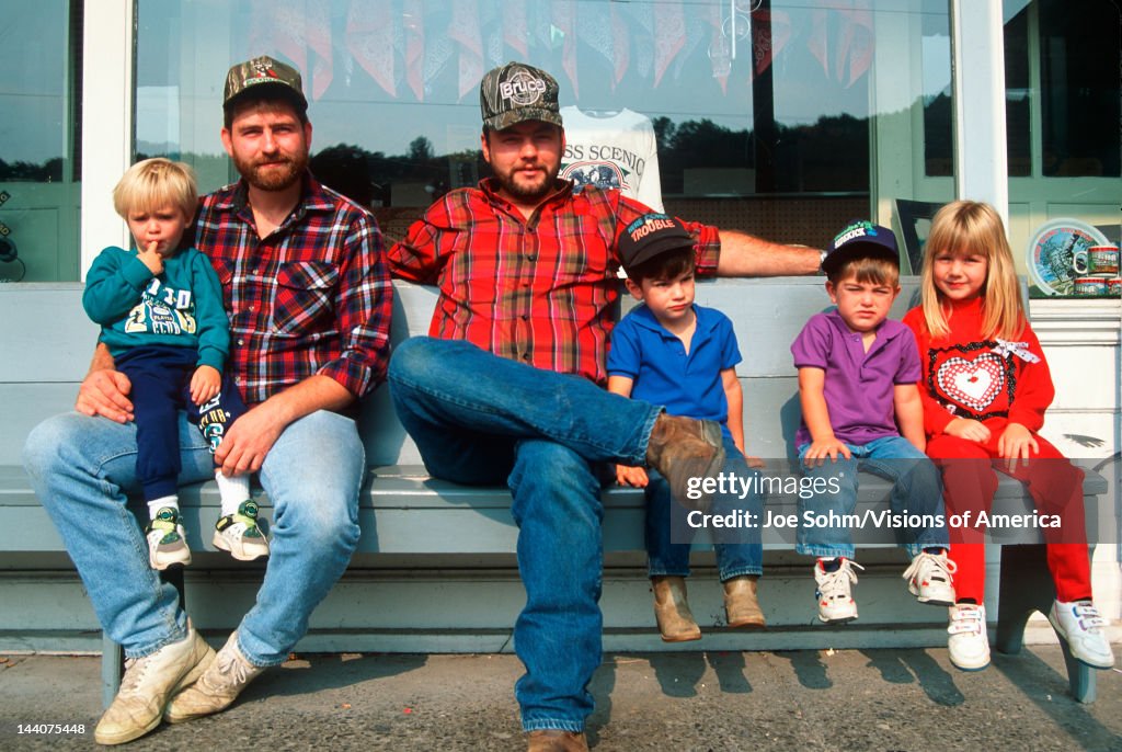 Two men and four children sitting on a bench, West VA