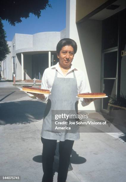 Food server carrying two cherry pies