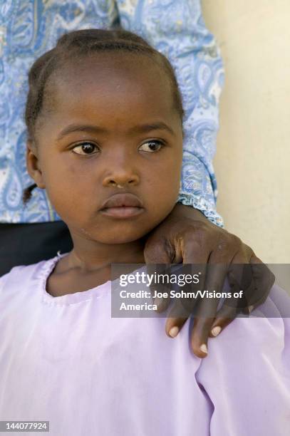 Young Kenya girl, infected with HIV/AIDS, stands beside Khadija Rama, founder of Pepo La Tumaini Jangwani, HIV/AIDS Community Rehabilitation Program,...