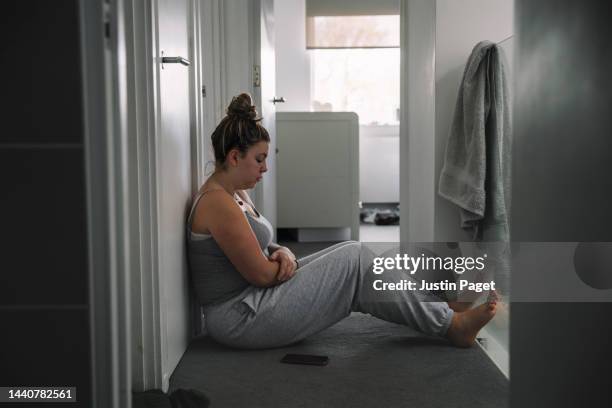 teenage girl sitting on landing floor with her smartphone beside her - negative emotion - donna triste foto e immagini stock