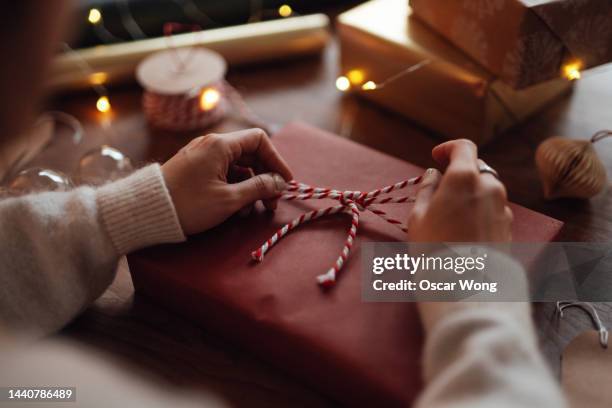 over the shoulder view of young woman wrapping christmas presents - wrapping stock pictures, royalty-free photos & images