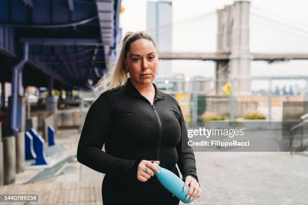 a young adult woman is doing a break during a fitness session in the city - buxom blonde stock pictures, royalty-free photos & images