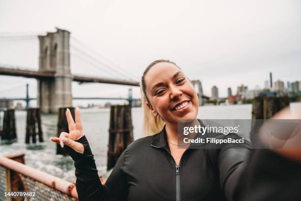 young woman is taking a selfie during a fitness session in the city - buxom blonde stock pictures, royalty-free photos & images