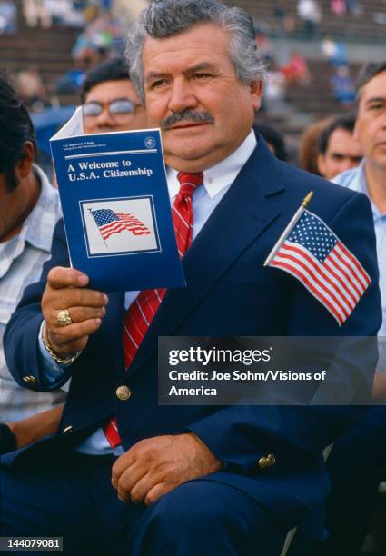 Latino American man with US citizenship book at induction ceremony in East Los Angeles, CA