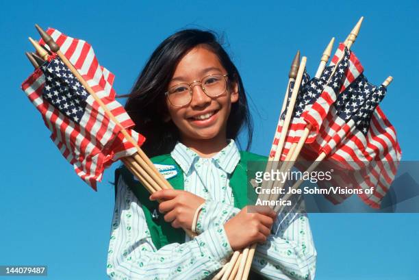 Filipino Girl Scout holding armful of American flags, Los Angeles, California
