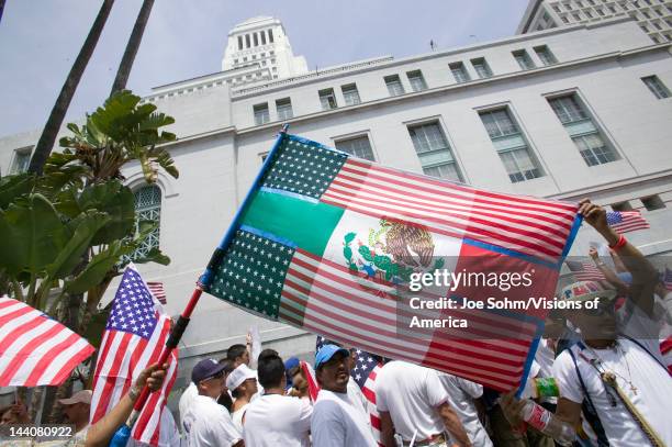 Mexican flag is superimposed over American flag in front of City Hall, Los Angeles, while hundreds of thousands of immigrants participate in march...