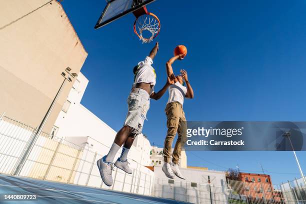 two young men playing street basketball in a city neighborhood - basketball sport stock pictures, royalty-free photos & images