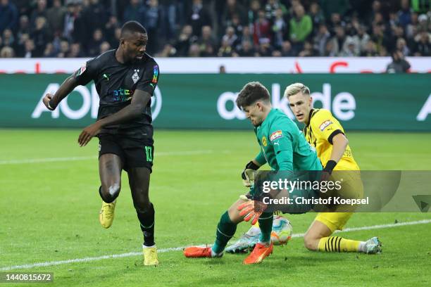 Marcus Thuram of Borussia Monchengladbach has a shot saved by Gregor Kobel and Nico Schlotterbeck of Borussia Dortmund during the Bundesliga match...
