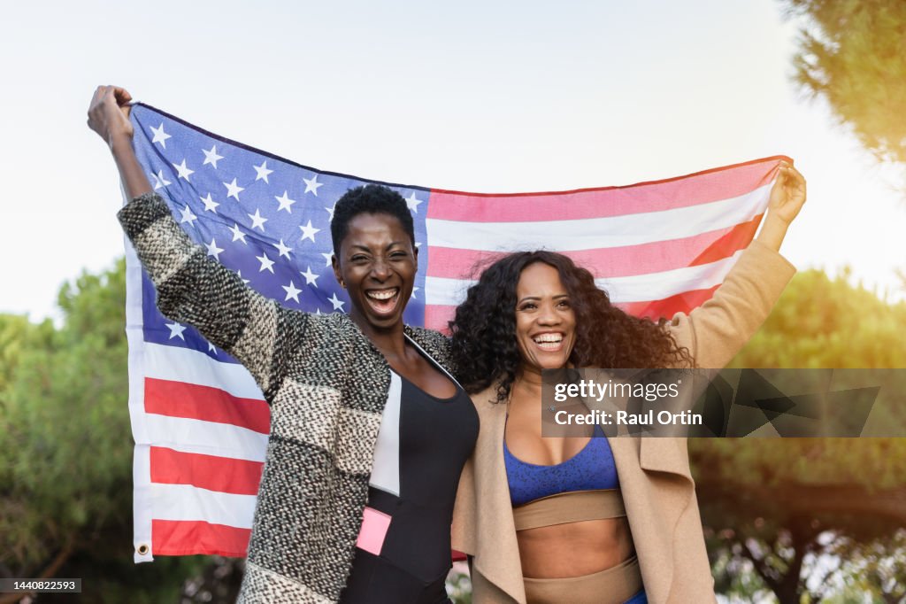 Portrait of happy women friend holding and waving usa american flag
