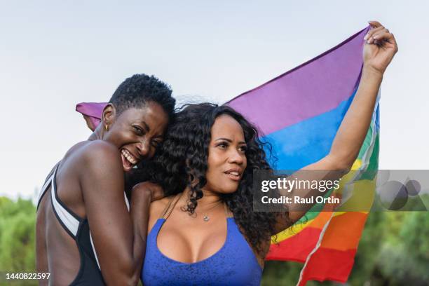 cheerful sportswear women friends celebrating waving lgbt rainbow flag - regenbogenfahne stock-fotos und bilder