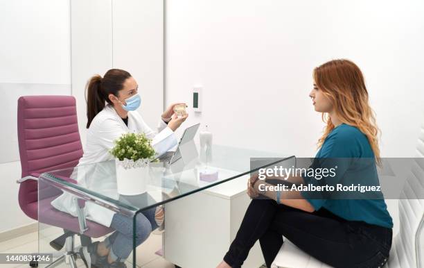 female dentist is meeting with a female patient and they are discussing about the treatment to be done - menselijke mond stockfoto's en -beelden