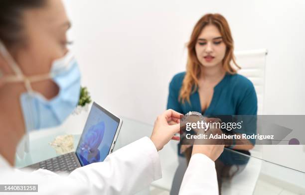 dentist woman showing a transparent dental aligner to a female patient - inside human mouth stock pictures, royalty-free photos & images