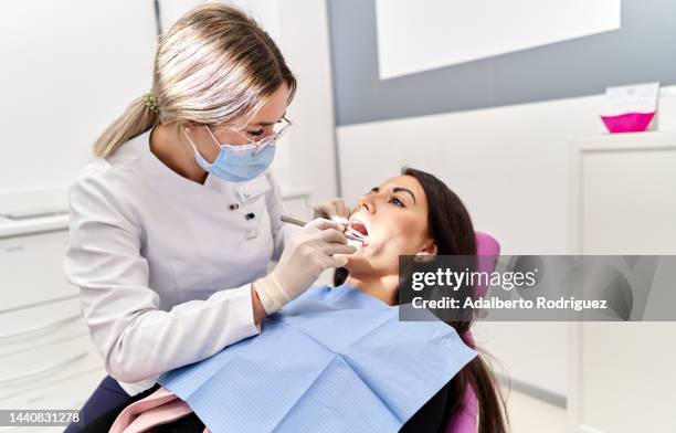 woman receiving a dental checkup in dentistry - dentista imagens e fotografias de stock